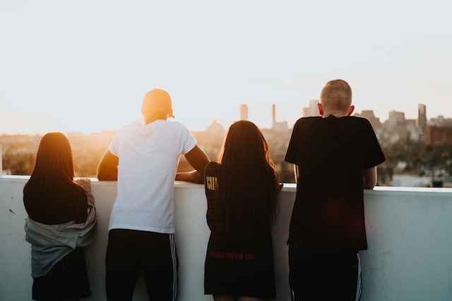 photo of 4 different young people looking out at a city 