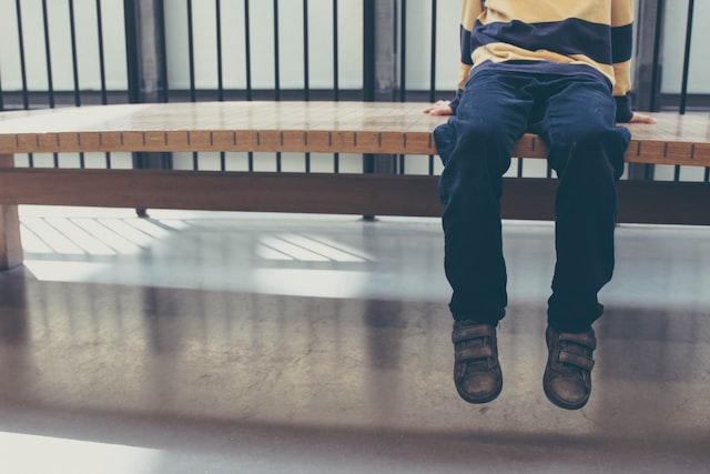 photo of child sitting on a bench in a hallway