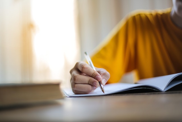 photo of a person holding a pen and writing