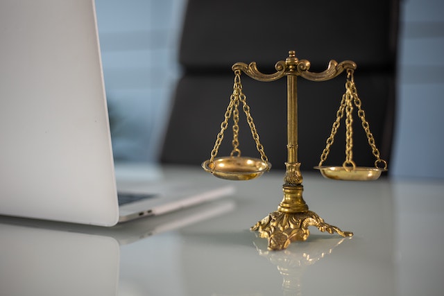 photograph of a gold justice scales with a laptop to the side