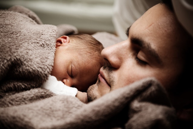 photo of a man with an infant sleeping on his chest