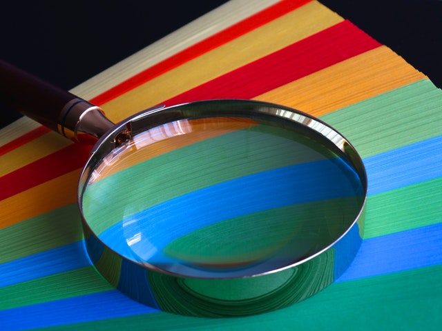 magnifying glass on top of papers of different colours