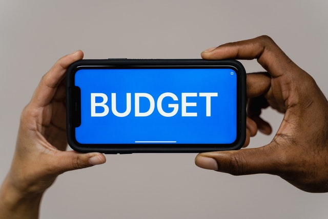 photograph of a person holding a mobile phone with the word budget on it